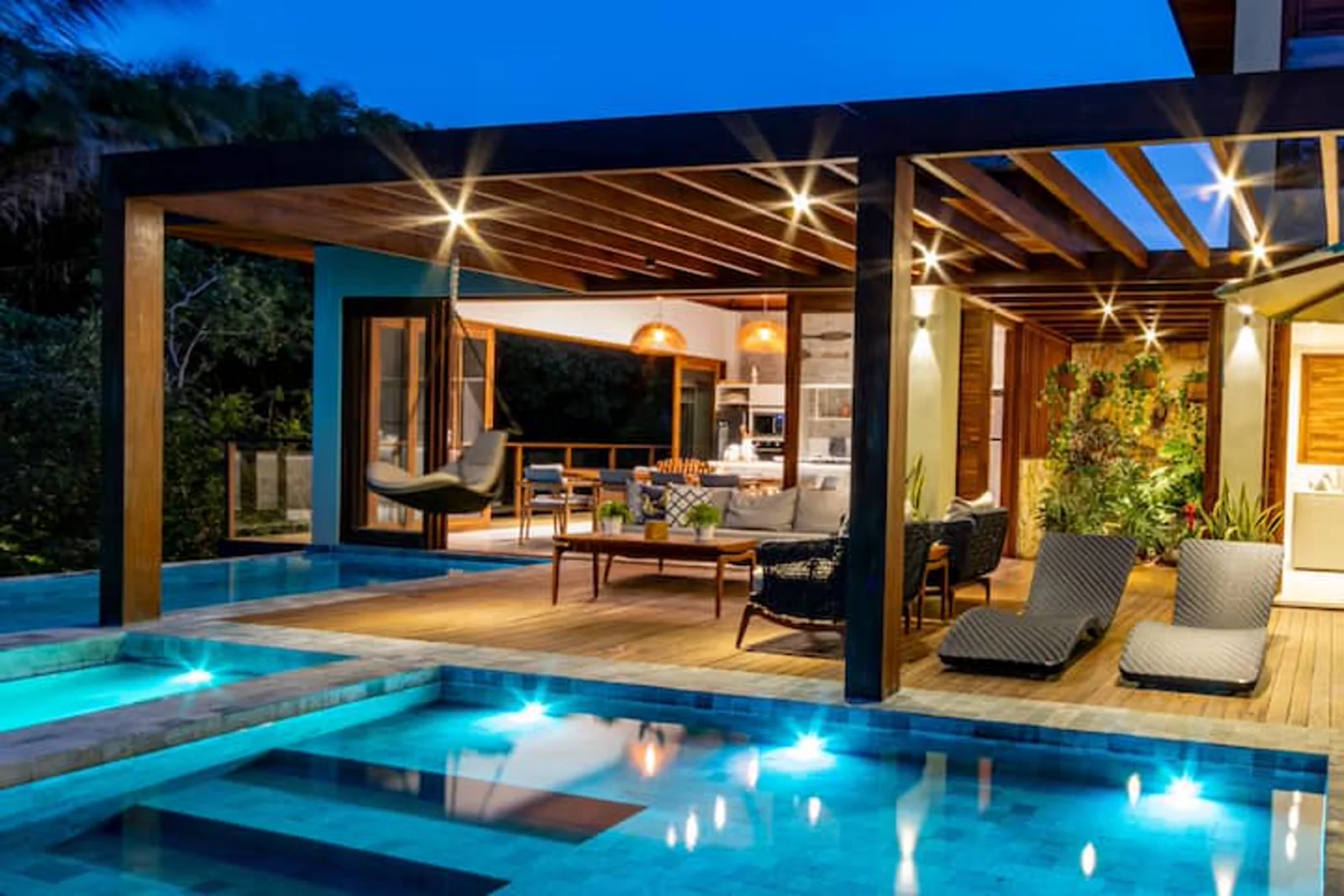A piscina integrada à cozinha e à área social, iluminada na hora azul