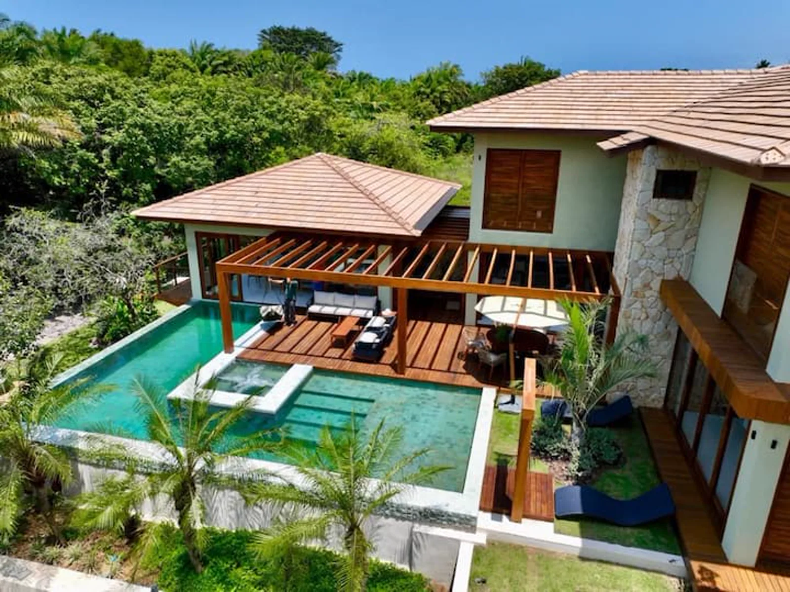 Vista aérea da vila, com a piscina e o pergolado entre a mata