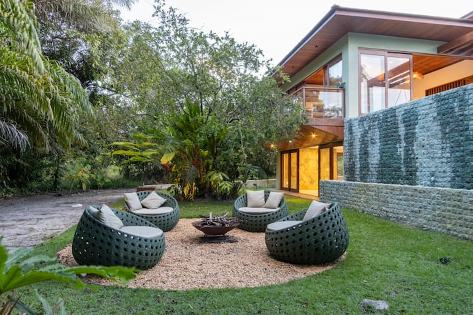 Lounge com fogueira ao entardecer, de frente para a casa