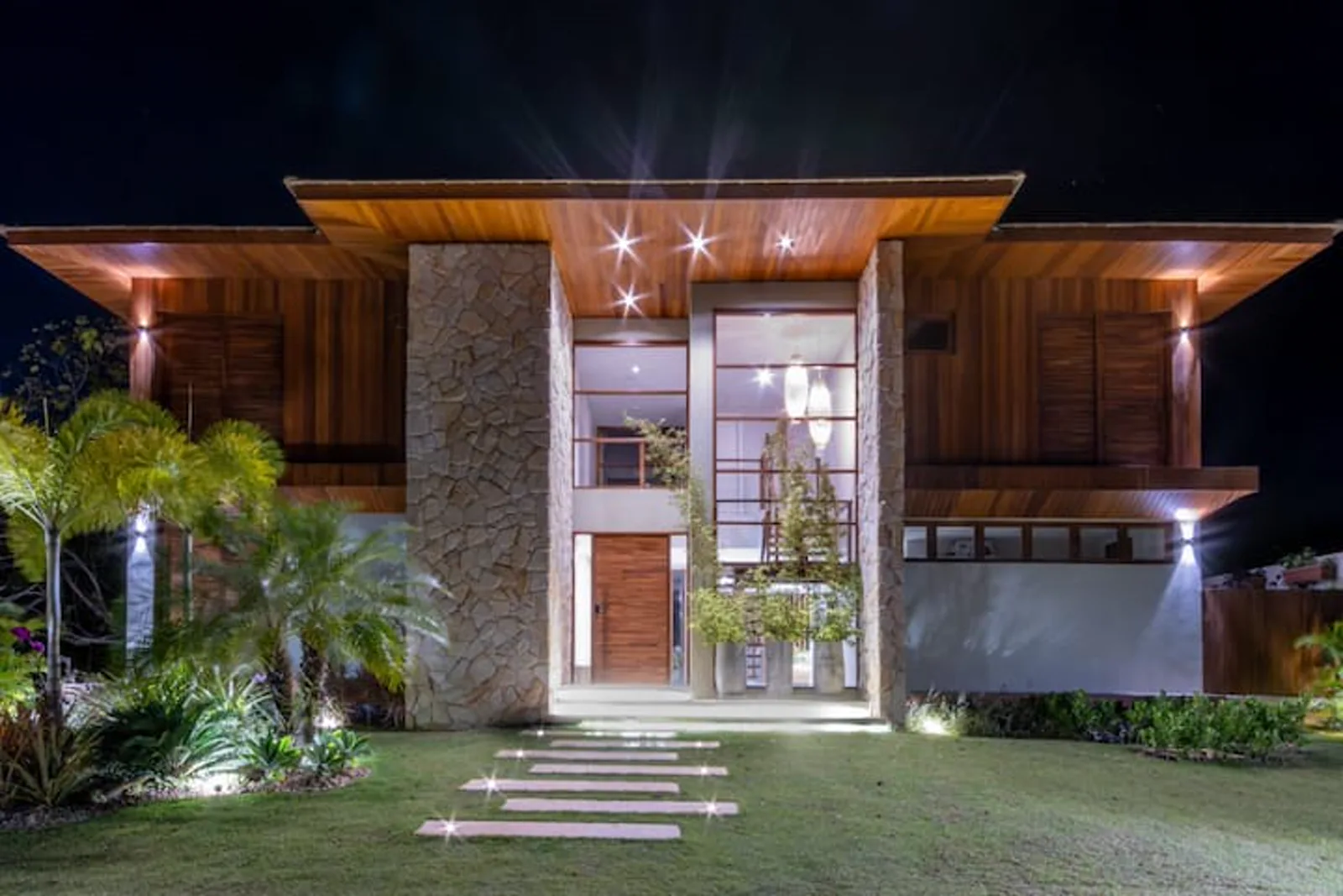 Fachada da vila iluminada à noite, em madeira e pedra