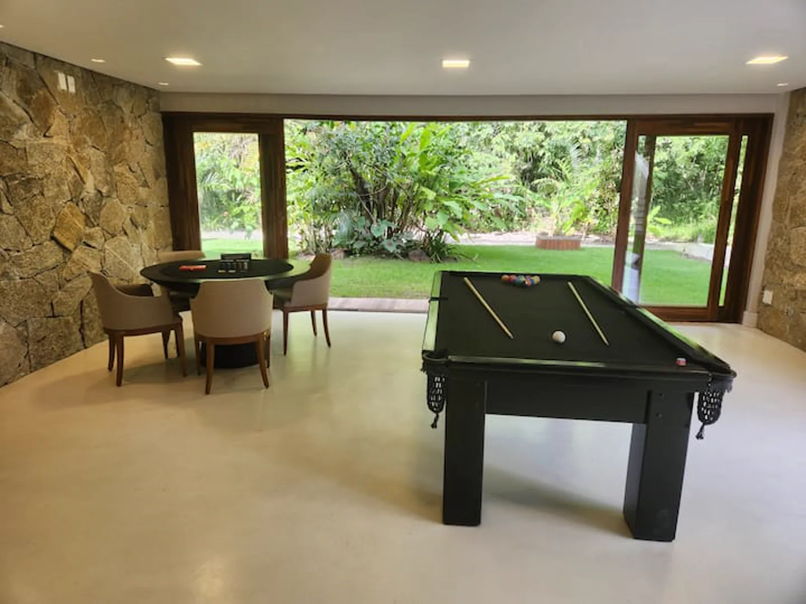 Sala de jogos com bilhar e mesa de jogos, aberta para o jardim